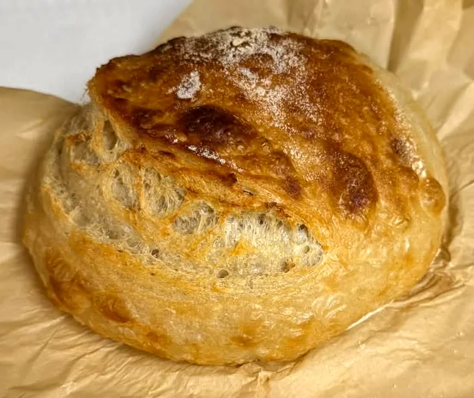 A crusty golden sourdough loaf on parchment