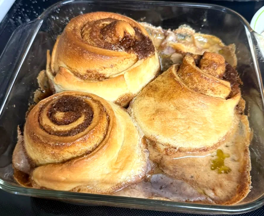 Three big swirled cinnamon rolls fresh from the oven in a glass baking dish
